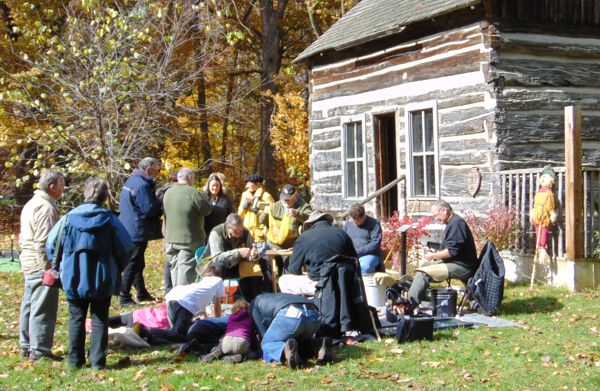 visitors enjoying a fall event in front of a cabin